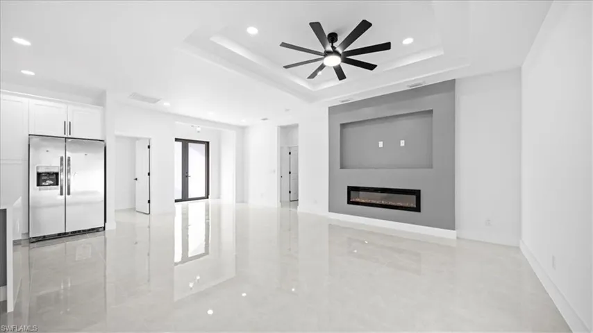 Unfurnished living room featuring recessed lighting, ceiling fan, a glass covered fireplace, and light marble finish floors