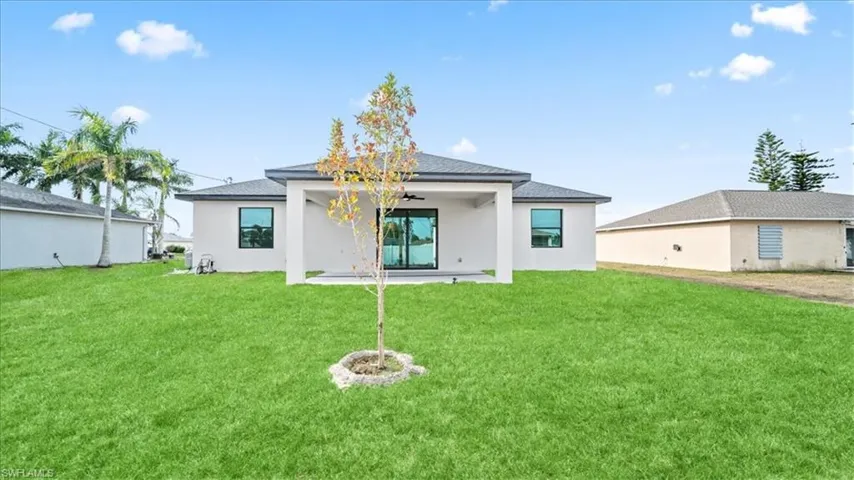 Back of property with a yard, a patio, ceiling fan, stucco siding, and a shingled roof