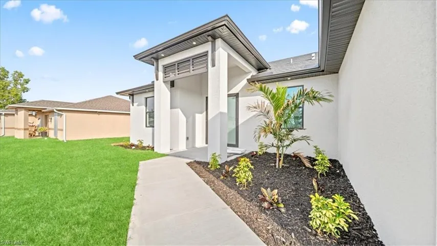 Entrance to property featuring stucco siding and a lawn