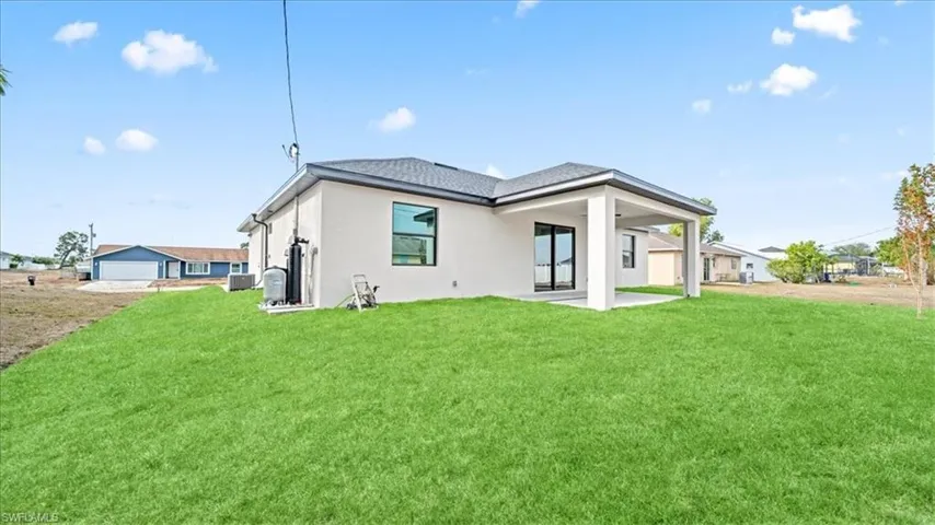 Back of property featuring a patio area, stucco siding, and a lawn