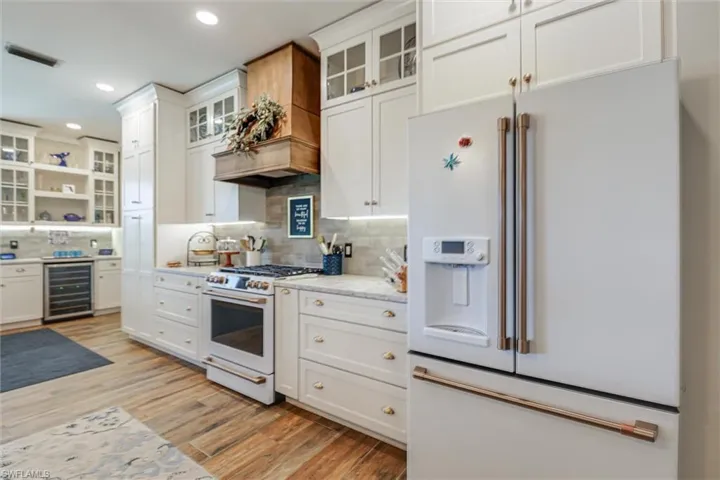 Kitchen featuring premium appliances, glass insert cabinets, white cabinets, open shelves, and recessed lighting
