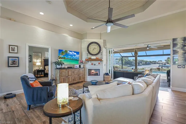 Living area with wood ceiling, wood finished floors, a tray ceiling, a fireplace, and crown molding