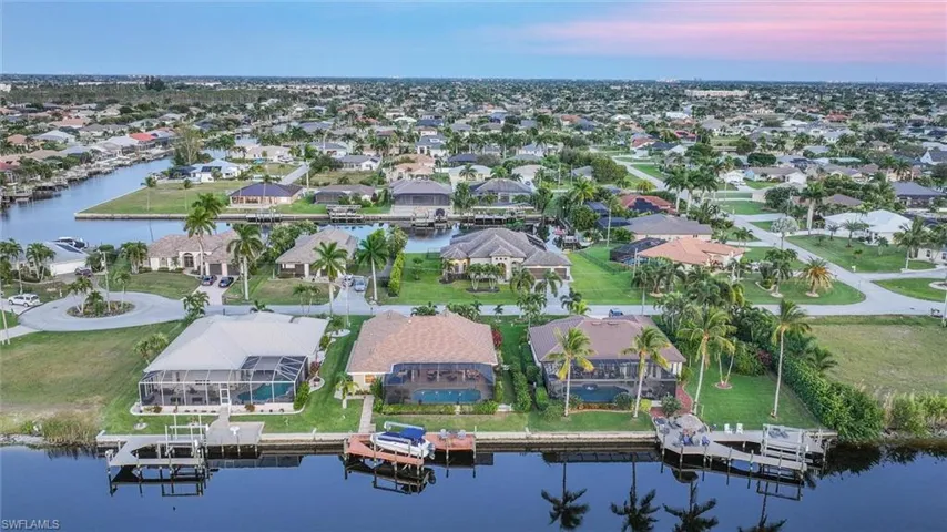 Aerial view of property and surrounding area featuring a nearby body of water and nearby suburban area
