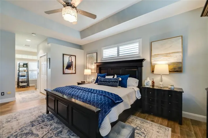 Bedroom with multiple windows, wood finished floors, ceiling fan, and a closet