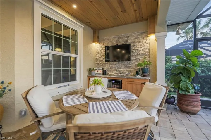 View of patio featuring outdoor dining space, a lanai, and beverage cooler