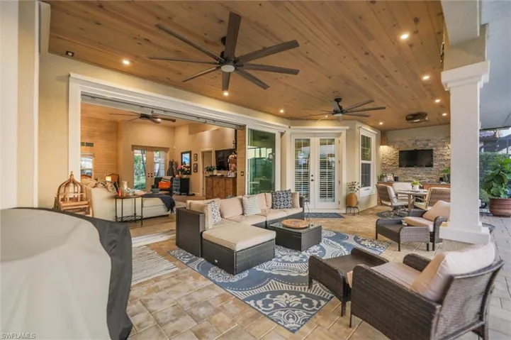 View of patio / terrace with french doors, an outdoor living space with a fireplace, outdoor dining space, and ceiling fan