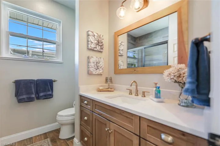 Full bathroom featuring a shower stall, vanity, dark wood-style flooring, and healthy amount of natural light