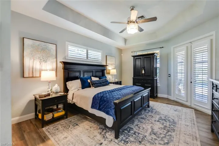 Bedroom with a tray ceiling, access to outside, ceiling fan, and dark wood-type flooring