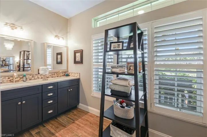 Bathroom with double vanity, dark wood-style flooring, and a chandelier