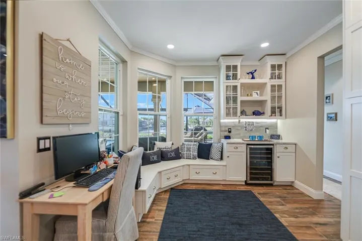 Home office featuring beverage cooler, recessed lighting, dark wood-style flooring, ornamental molding, and wet bar
