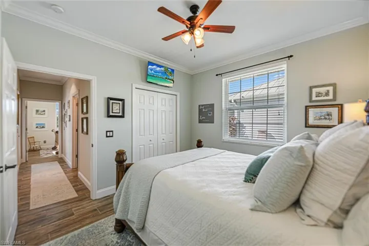 Bedroom featuring crown molding, ceiling fan, a closet, and dark wood-style flooring