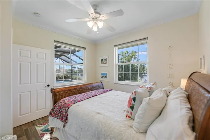 Bedroom with wood finished floors, ceiling fan, and ornamental molding