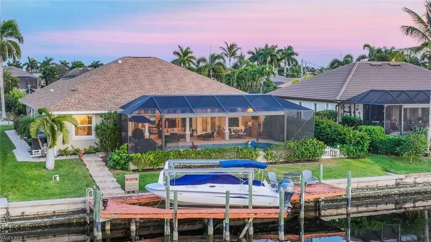 Back of property at dusk with a lawn, a sunroom, and glass enclosure