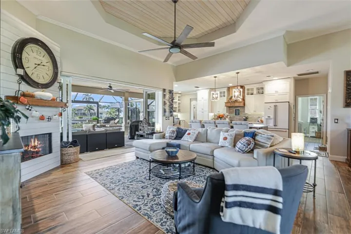 Living room featuring a raised ceiling, a fireplace, wood-type flooring, wood ceiling, and ornamental molding