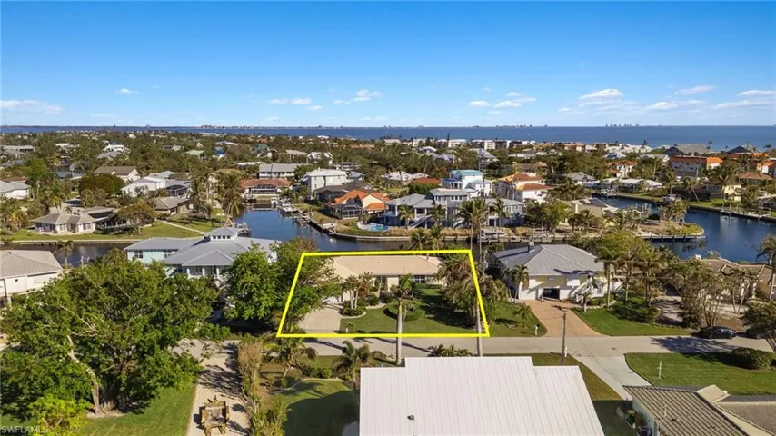 Aerial perspective of suburban area featuring property parcel outlined and a nearby body of water