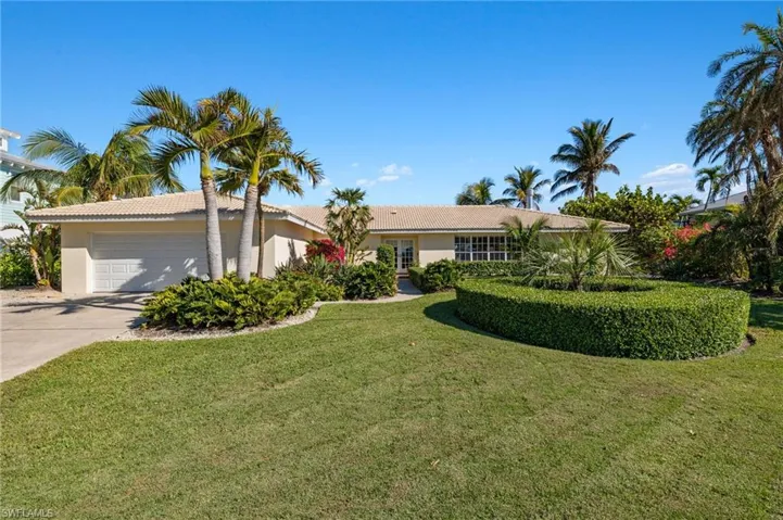 Ranch-style house with driveway, a garage, a tile roof, a front lawn, and stucco siding
