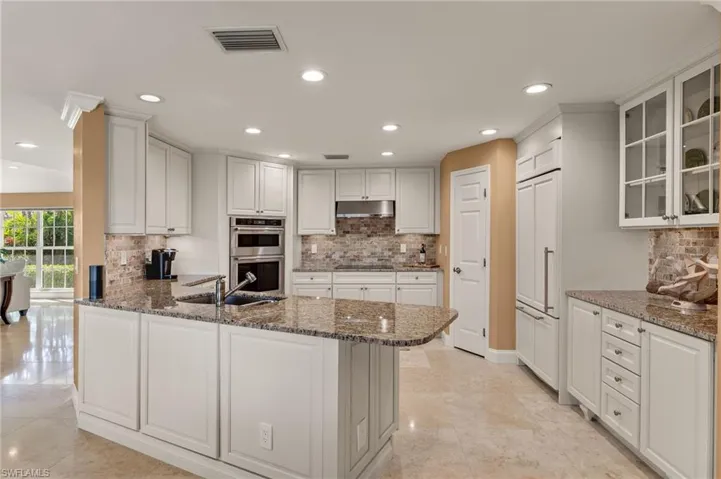 Kitchen featuring decorative backsplash, dark stone counters, a peninsula, recessed lighting, and white cabinetry