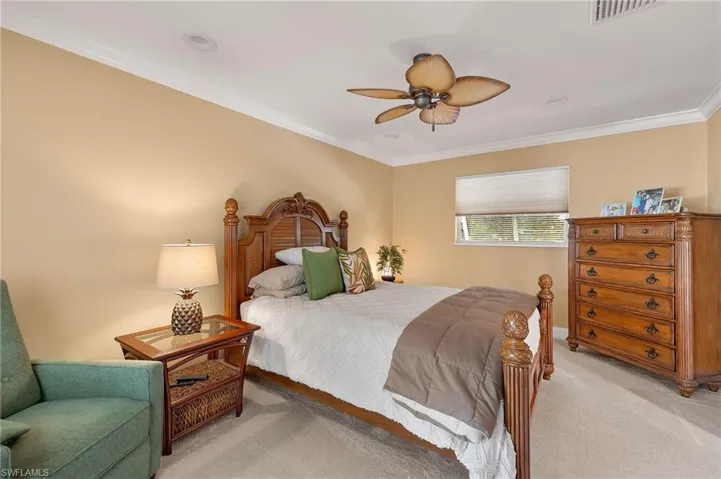 Carpeted bedroom with ornamental molding and ceiling fan