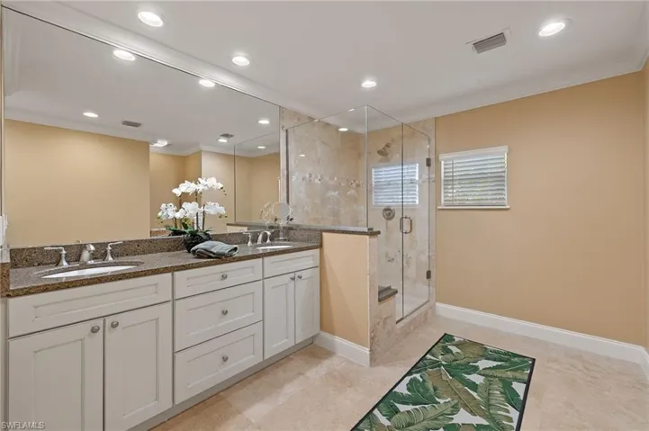 Full bathroom featuring crown molding, a stall shower, double vanity, recessed lighting, and light tile patterned floors