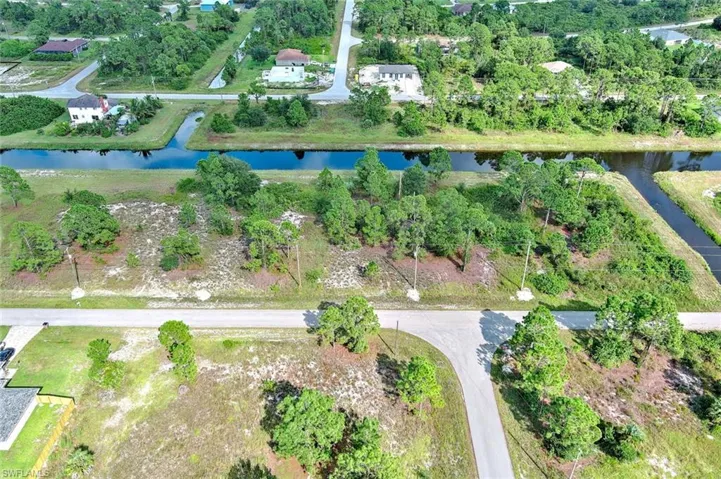 Aerial view of property and surrounding area with a nearby body of water and a tree filled landscape