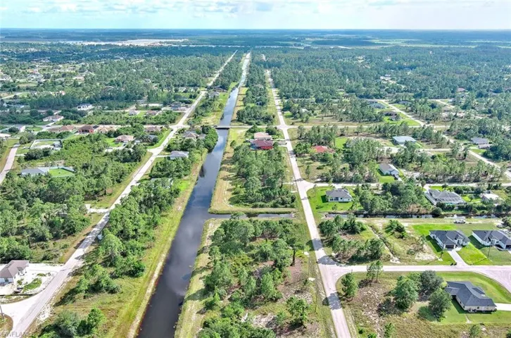 Aerial view of property and surrounding area featuring a nearby body of water and nearby suburban area