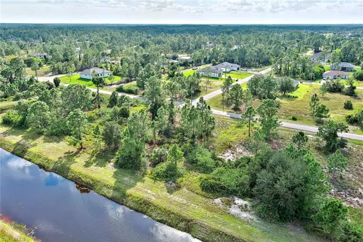 Aerial view of property and surrounding area with a nearby body of water and a forest