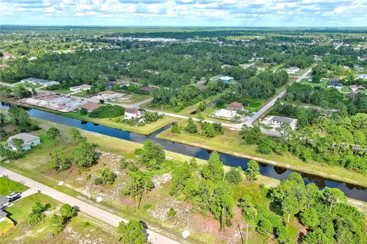 Aerial view of property and surrounding area featuring a nearby body of water and nearby suburban area