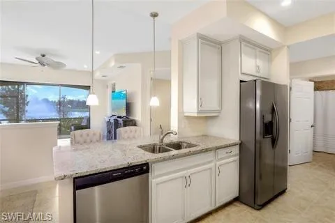 Kitchen featuring a sink, stainless steel appliances, a peninsula, and light stone countertops
