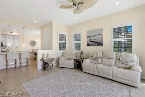 Living room with a ceiling fan, light tile patterned flooring, and recessed lighting