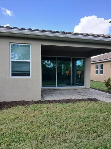 Rear view of house featuring a yard, stucco siding, a patio, and a tiled roof