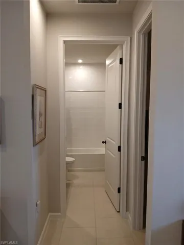 Hallway featuring light tile patterned floors and baseboards