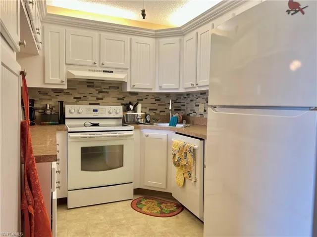 Kitchen featuring white appliances, white cabinets, and decorative backsplash