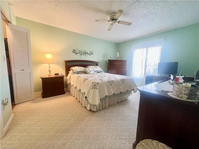 Bedroom with carpet floors, a ceiling fan, a textured ceiling, and a closet
