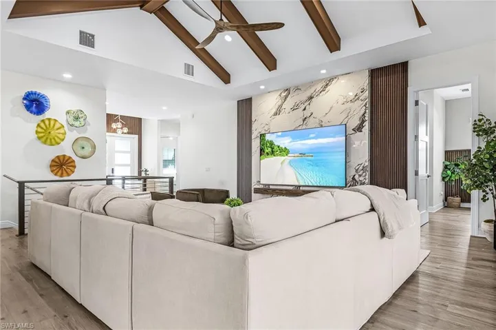 Living room featuring beam ceiling, light wood-style floors, ceiling fan, recessed lighting, and high vaulted ceiling