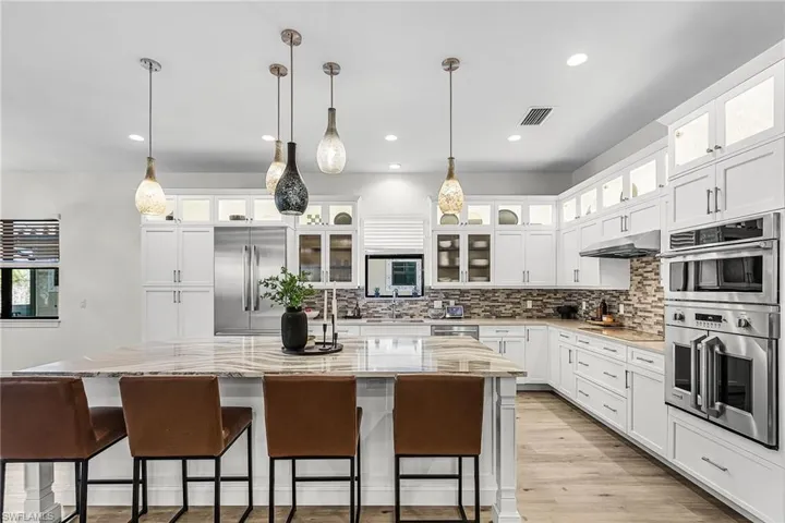 Kitchen with a kitchen bar, a kitchen island, tasteful backsplash, white cabinetry, and recessed lighting