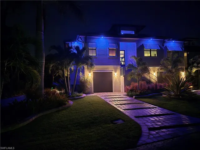 View of front facade with a lawn, decorative driveway, stucco siding, and an attached garage