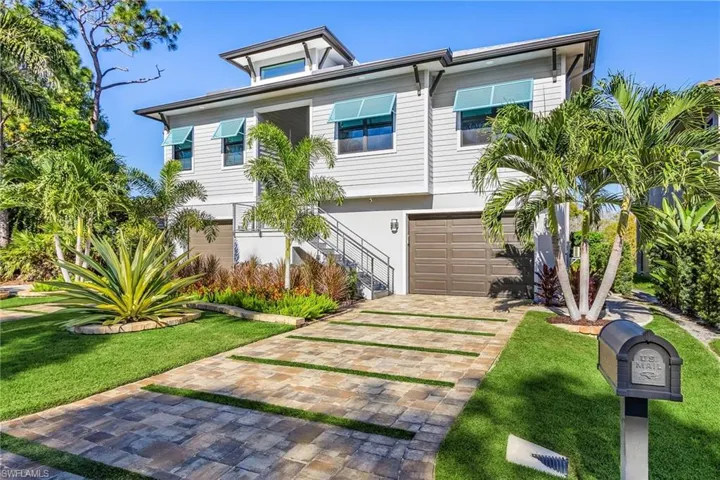 View of front of home featuring stairway, a front lawn, decorative driveway, and a garage