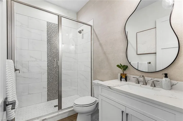 Bathroom featuring a shower stall, vanity, and tile walls