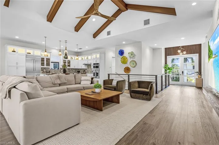 Living room with beam ceiling, french doors, wood finished floors, recessed lighting, and a ceiling fan