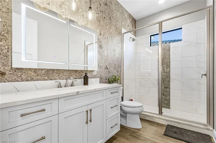 Bathroom featuring vanity, a stall shower, and light wood-style flooring