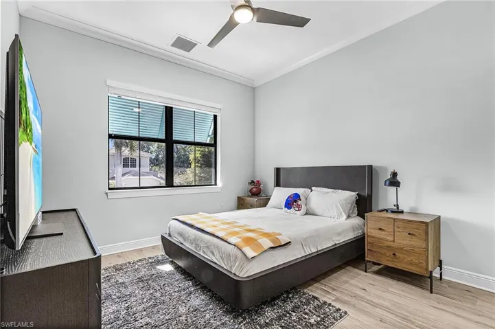 Bedroom featuring light wood-style flooring, ornamental molding, and ceiling fan