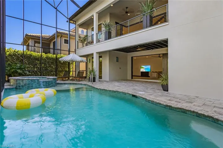 View of pool with a lanai, a patio area, a pool with connected hot tub, a sunroom, and a balcony