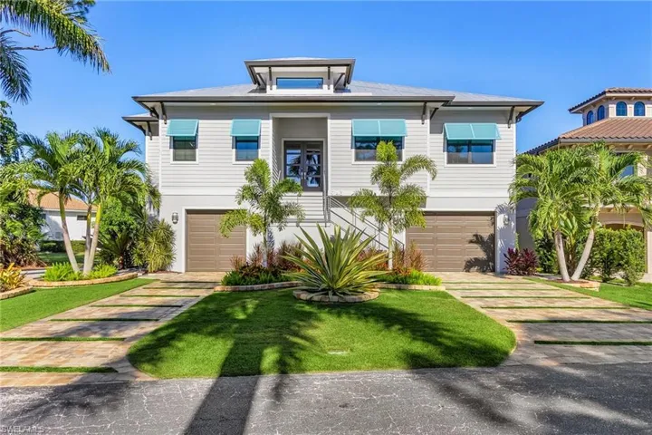 Coastal home featuring a front lawn, driveway, and an attached garage