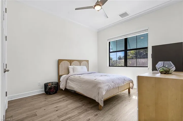 Bedroom with light wood finished floors, a ceiling fan, and crown molding