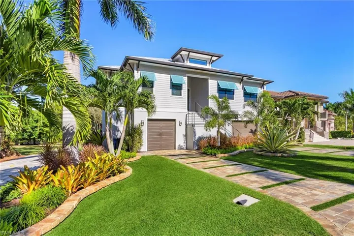 View of front of property with stairs, a front yard, driveway, and an attached garage