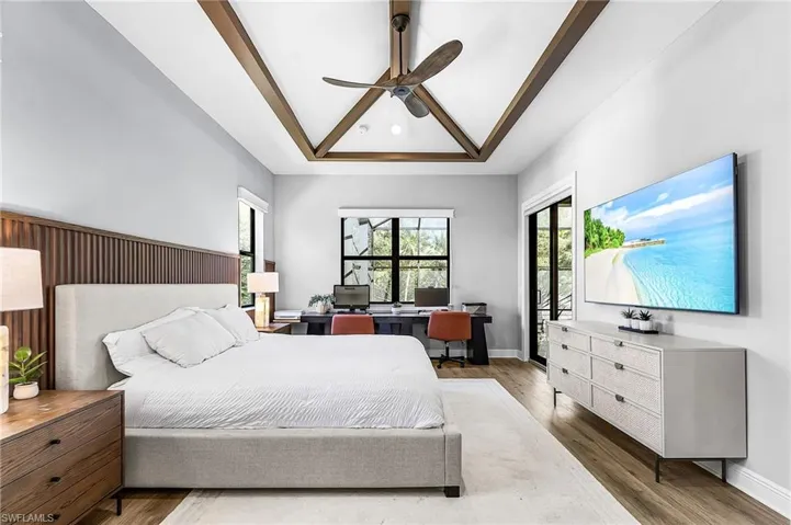Bedroom with a raised ceiling, a desk, wood finished floors, and ceiling fan