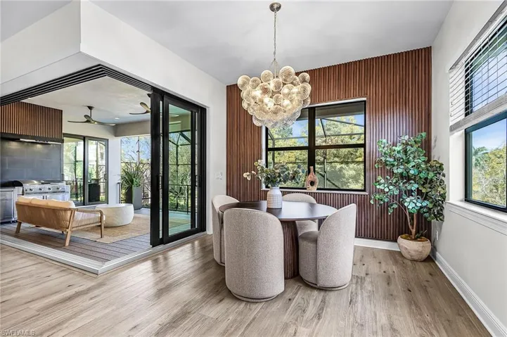 Dining area with a chandelier, light wood finished floors, ceiling fan, and wood walls