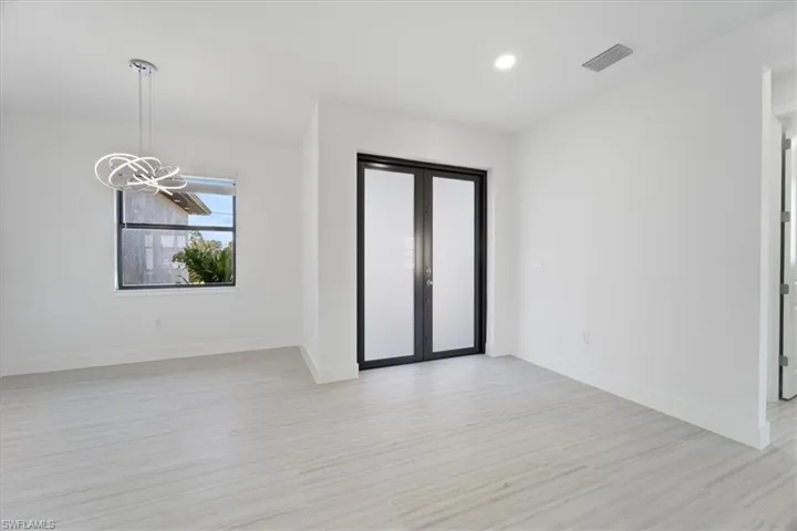 Unfurnished room with baseboards, visible vents, light wood-style floors, and a notable chandelier