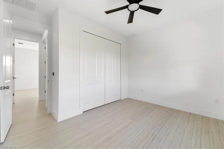Unfurnished bedroom featuring light wood-style floors, baseboards, and a closet