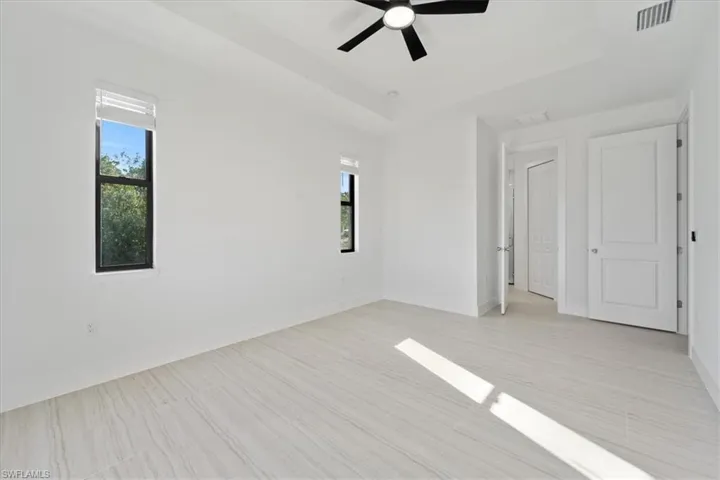Spare room featuring baseboards, a tray ceiling, visible vents, and ceiling fan